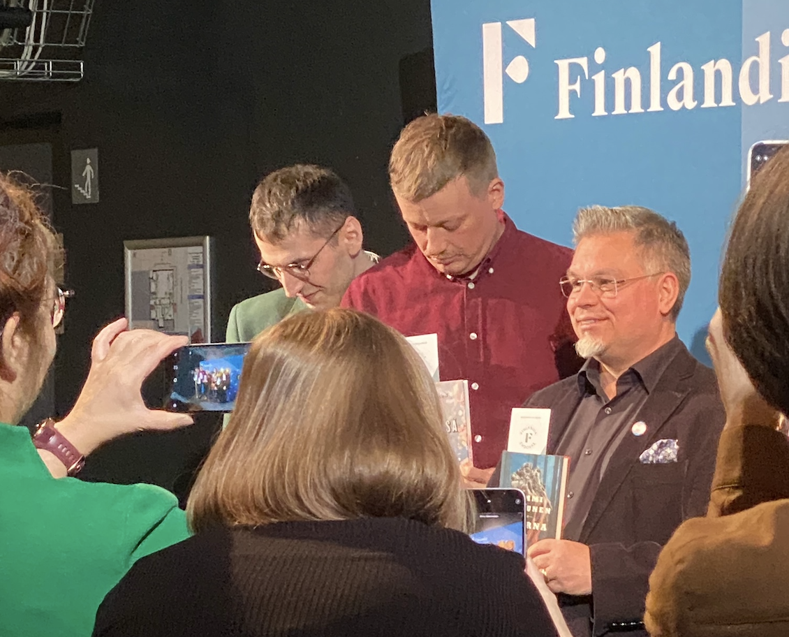 Finlandia-ehdokkaita kuvausseinää vasten ja edessä innokkaita kuvaajia.